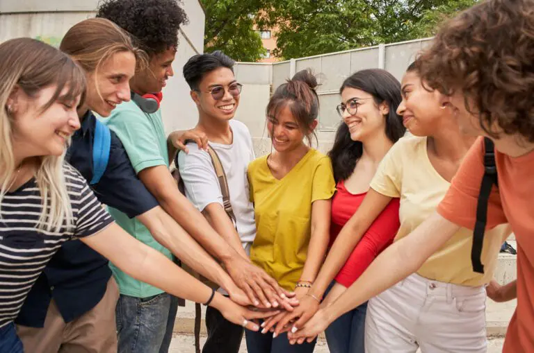 Group of friends stacking hands outdoors.
