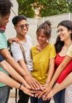 Group of friends stacking hands outdoors.